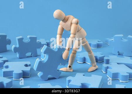 Holzpuppe, die Puzzle zusammenstellt. Problemlösungskonzept Stockfoto