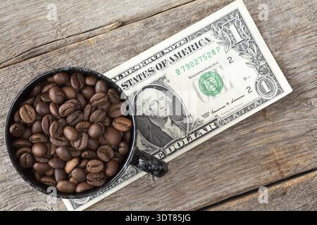 Tasse Kaffee Bohnen auf Dollar Banknote repräsentieren hohe oder niedrige Preise für Kaffee am Aktienmarkt Stockfoto