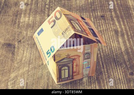 Haus von Euro-Banknoten auf einem hölzernen Hintergrund aus Stockfoto
