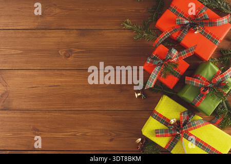Bunte Geschenkboxen auf Holzoberfläche mit Kiefernzweigen und Glocken für die Weihnachtsfeier Stockfoto
