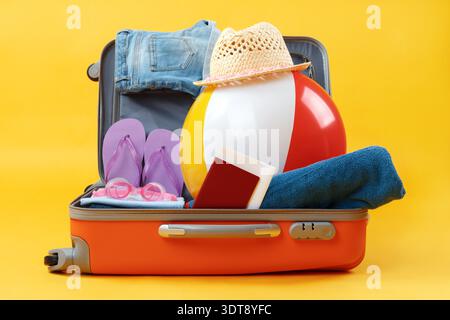 Öffnen Sie den ganzen Koffer mit Gegenständen zur Entspannung auf gelbem Hintergrund. Stockfoto