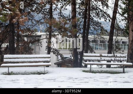 Zwei schneebedeckte Holzbänke in einer schneebedeckten Bergkulisse. Das Bild ist Teil einer Serie, die an einem verschneiten Tag im Trentino in Norditalien aufgenommen wurde Stockfoto