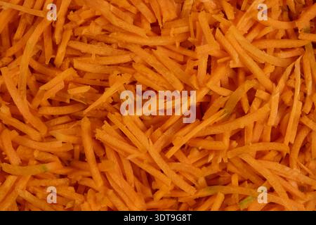 Lebendige Textur von geschredderten rohen Karotten, Makroansicht. Stockfoto