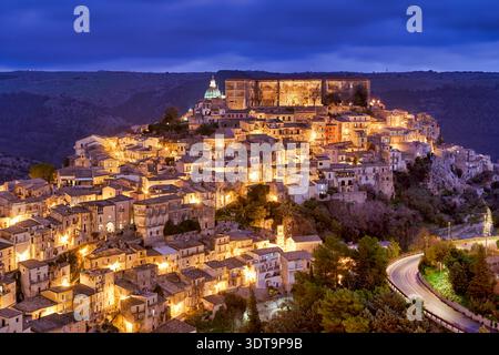 Ragusa Ibla zeigt seinen Charme während des Sonnenuntergangs mit warmen Lichtern aus den Gebäuden. Die Skyline spiegelt die Schönheit der Altstadt wider. Stockfoto