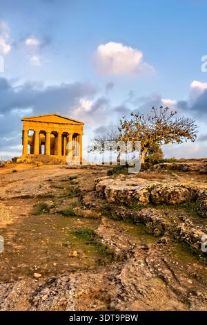 Menschen besuchen den Tempel der Concordia, der sich im Tal der Tempel in Agrigent Sizilien während des Sonnenuntergangs befindet. Stockfoto