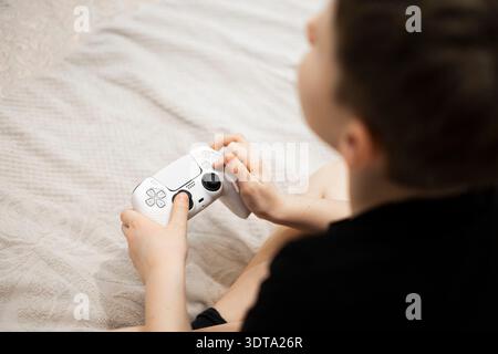 Ein Kind hält ein Spielerpad in der Hand und spielt ein Videospiel. Stockfoto