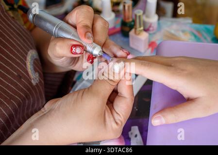 Nahaufnahme eines professionellen Nageltechnikers, der Maniküre an der Hand eines Kunden durchführt. Konzept der Schönheitspflege, Nagelstudio und Selbstpflege Stockfoto