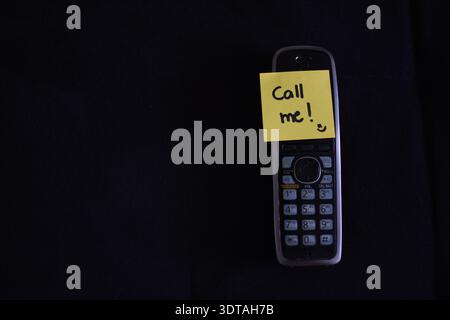 Gelber Haftnotiz mit der Aufschrift „Call me“ auf dem Smartphone auf schwarzem Hintergrund. Konzept über Kommunikation, Erinnerungen, Verbindung, Motivation und Moderne Stockfoto