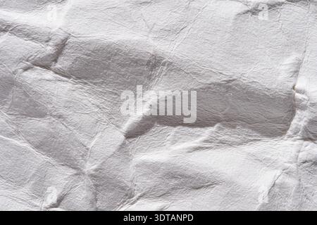 Nahaufnahme einer zerknitterten, strukturierten weißen Papieroberfläche mit Schatten und Lichtern. Stockfoto