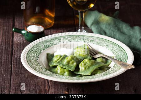 Grüner Spinat Ravioli mit Cremesauce und Weißwein auf rustikalem Tisch, italienische Küche. Stockfoto