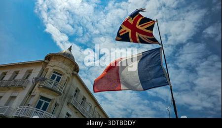 Soulac-sur-Mer, Frankreich - 7. Juni 2025. Die britische Jack-Flagge und die französische Staatsflagge auf einem Flaggschiff flattern im Wind gegen den blauen Himmel Stockfoto