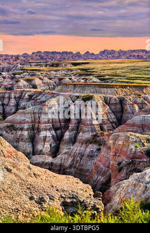 Big Badlands Overlook steht im Badlands National Park, South Dakota, USA. Die malerische Aussicht bietet farbenfrohe erodierte Felsformationen und Sedimentschichten unter einem bewölkten Himmel bei Sonnenuntergang Stockfoto