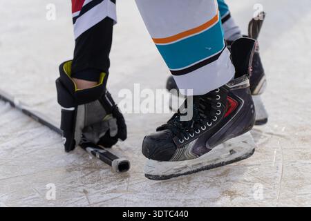 Eishockeyspieler in Skates greift auf zerkratztes Eis, Nahaufnahme von Handschuh, Skate Klinge und Uniformsocken, Wintersport Training und Bereitschaft Conc Stockfoto