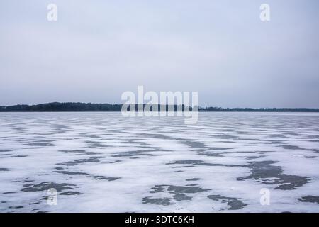 Gefrorene Seenoberfläche bedeckt mit gemustertem Eis und Schnee im Winter Stockfoto