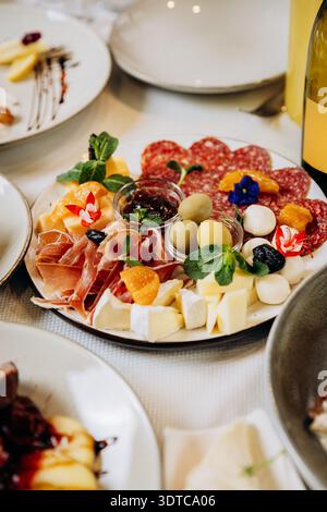 Gourmet-Vorspeisenplatte mit Käse, Oliven und geräuchertem Fleisch, serviert am Restauranttisch Stockfoto