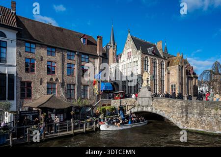 Brügge, Belgien - 14. Februar 2026: Touristen auf einem Kanalboot, das unter der Johannes-Nepomuk-Brücke mit der Statue des Heiligen Johannes Nepomuk von Pieter vorbeifährt Stockfoto