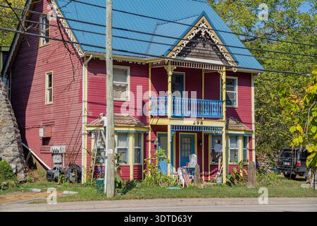 Arkansas, 21. SEP 2024 - zwei Arbeiter malen das leuchtend rote Äußere und die blaue Verkleidung eines Hauses im klassischen viktorianischen Stil mit Giebeldach und Veranda Stockfoto