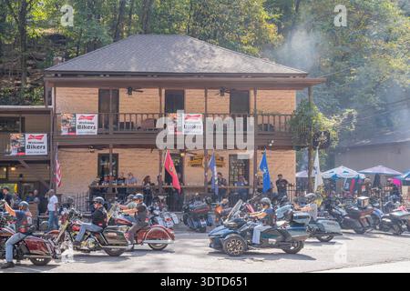 Arkansas, 21. September 2024 – Motorradfahrer in Helmen und Lederausrüstung treffen sich vor einer rustikalen, zweistöckigen Lodge, die mit Bannern und Fahnen geschmückt ist Stockfoto
