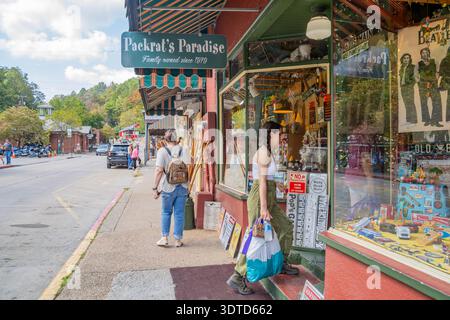 Arkansas, 21. September 2024 - zwei Frauen laufen auf einem Bürgersteig vorbei an einem farbenfrohen Vintage-Laden namens Packrat's Paradise auf einer sonnigen Hauptstraße. Stockfoto