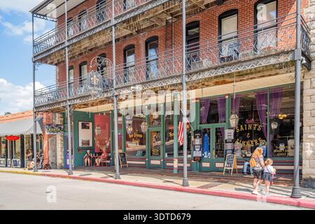 Arkansas, 21. September 2024 - zweistöckiges Backsteingebäude mit kunstvollen Eisenbalkonen und Ladenfronten in einer sonnigen Straße in New orleans. Stockfoto