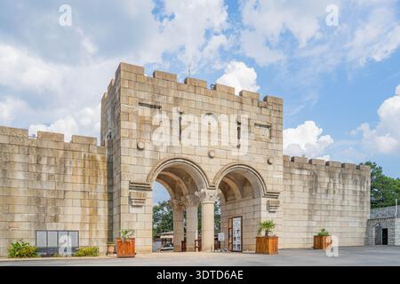 Arkansas, 21. September 2024 - Steines Burgtor mit zwei gewölbten Eingängen und zinnenförmigen Wänden unter hellblauem Himmel mit flauschigen weißen Wolken. Stockfoto