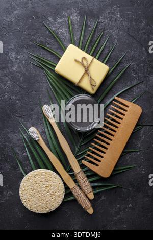 Natürliche Bambus Zahnbürsten, schwarzes Zahnpulver, Haarkamm, Seife und Schwamm auf dunkelgrauem Hintergrund, Null-Abfall-Produkte, natürliche Mundhygiene, Kopie Stockfoto