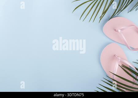 Sommer Urlaub, rosa Strand Hausschuhe Flip Flops und Palm Tree Branch auf blauem Hintergrund Stockfoto