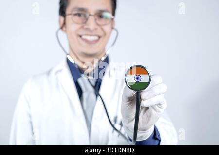 Medizinischer Fachmann zeigt Stethoskop mit der Flagge von Indien. Lächelnder Arzt, der Stethoskop mit indischer Flagge auf weißem Hintergrund zeigt Stockfoto