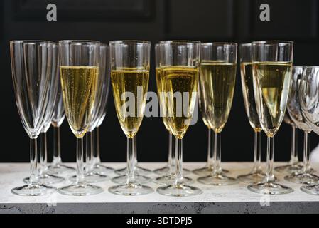 Eine Reihe Sektflöten gefüllt mit prickelnden Erfrischungen, die besondere Anlässe feiern. Ein Toast auf die Feier: Weingläser in einer Reihe Stockfoto