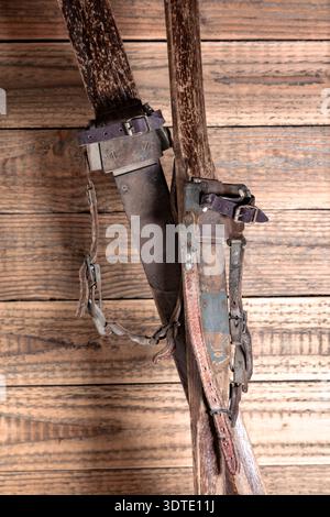 Antike Holzskier mit Lederbindungen vor rustikalem Holzhintergrund Stockfoto