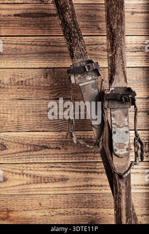 Antike Holzskier mit Lederbindungen vor rustikalem Holzhintergrund Stockfoto