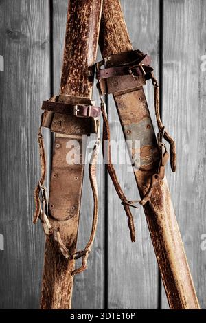 Antike Holzskier mit Lederbindungen auf grauem Holzhintergrund Stockfoto