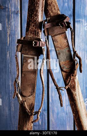 Antike Holzskier mit Lederbindungen auf blauem Holzhintergrund Stockfoto