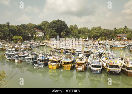 Ganz in der Nähe des Tangalle Harbor an der Südküste Sri Lankas, eine Mischung aus Fischerbooten, Katamaranen und kleinen Motorschiffen, die in ruhigem Türkis vor Anker liegen Stockfoto