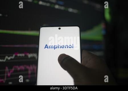 Ein Telefon mit dem Amphenol-Logo vor den Börsencharts Stockfoto