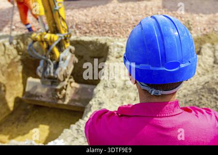 Blick von hinten auf Bauarbeiter, Vorarbeiter, mit blauem Sicherheitshelm auf der Baustelle, Projekt läuft Stockfoto