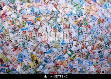 Viele Banknoten unterschiedlicher Währung. Eine große Menge von zufälligen Geldrechnungen aus der Nähe. Währungsumtausch-Konzept Stockfoto