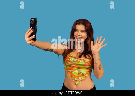 Gen z Frau erstellt Inhalte, nimmt ein Video auf, während sie winkt Stockfoto