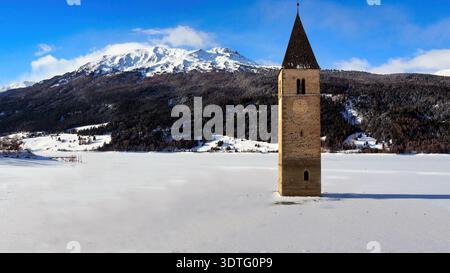 Gesunkener Glockenturm des Reschensees unter blauem Winterhimmel. Ein klarer, sonniger Wintertag am Reschensee in Südtirol, Italien. Stockfoto