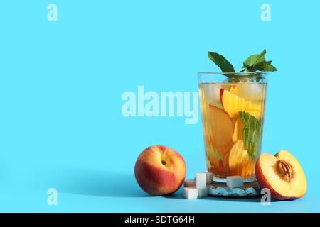 Glas leckerer Pfirsicheistee auf blauem Hintergrund, Nahaufnahme Stockfoto