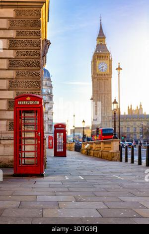 Selektive Fokusansicht einer roten Telefonzelle vor dem Big Ben Uhrturm in London, Westminster, während Sonnenaufgang ohne Menschen Stockfoto