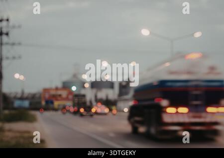 Ein verschwommenes Bild einer Straße mit Fahrzeugen, die von der Kamera wegfahren, mit roten Bremslichtern und Straßenbeleuchtung, die die Szene beleuchten. Stockfoto
