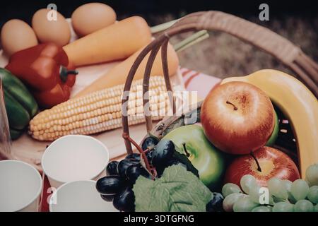 Ein Korb gefüllt mit einer Vielzahl von frischem Obst und Gemüse, einschließlich Äpfel, Bananen, Trauben, Mais, Karotten, Paprika und Eier. Stockfoto