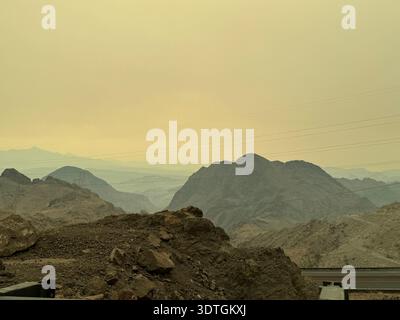 Eine düstere Berglandschaft in der Wüste nahe dem Hoover Dam mit übereinander gestuften felsigen Hügeln unter gelbem Himmel im amerikanischen Südwesten, Nevada–Arizona, USA. Stockfoto
