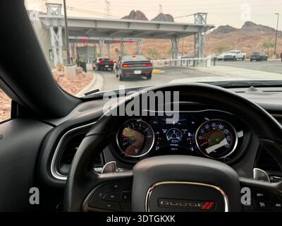 Blick aus dem Inneren eines Autos, das sich dem Hoover Dam-Sicherheitskontrollpunkt nähert, mit Fahrzeugen auf der Zufahrtsstraße, Grenze zwischen Nevada und Arizona, USA. Stockfoto