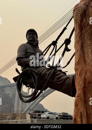 Statue eines Kletterers mit Blick auf die Mike O'Callaghan–Pat Tillman Memorial Bridge in der Nähe des Hoover Dam, Grenze zwischen Nevada und Arizona, USA. Stockfoto