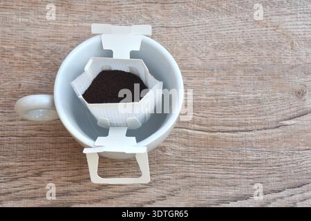 Kaffeetropfpulver mit Filter und Holzlöffel in Becherglas auf dem Tisch Stockfoto