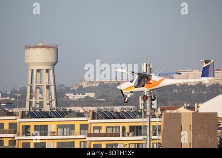 Leichte Flugzeuge fliegen tief über städtische Gebäude und Solarpaneele Stockfoto