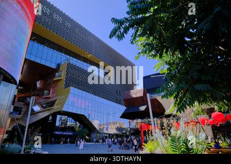 Dynamischer, flacher Blick auf ein modernes Architekturgebäude mit auffälligen geometrischen Mustern und Glasfassaden vor einem klaren blauen Himmel. Stockfoto