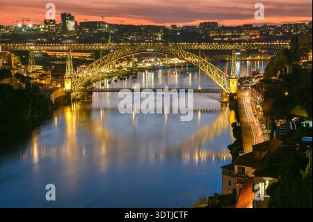 Blick auf die Brücke Dom Luis I und den Stadtteil Bairro da Ribeira in Porto, Portugal, in der Abenddämmerung. Stockfoto